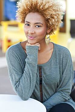 Black woman resting chin in hand outdoors