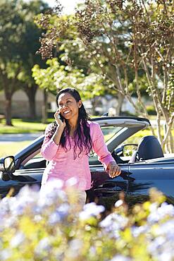 Indian woman talking on cell phone near car