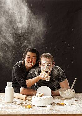 Woman shoving cake in face of boyfriend