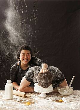 Woman shoving face of boyfriend in cake