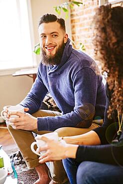 Couple drinking coffee on sofa in living room