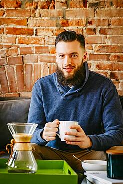 Man drinking coffee on sofa in living room