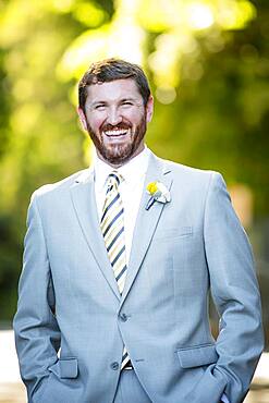 Caucasian groom laughing in garden