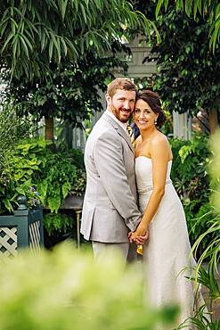 Caucasian bride and groom hugging in garden