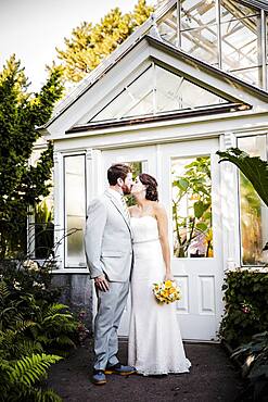 Caucasian bride and groom kissing in garden