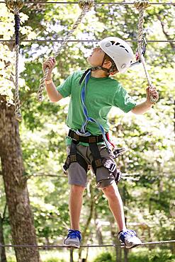 Caucasian boy balancing on slackline in forest