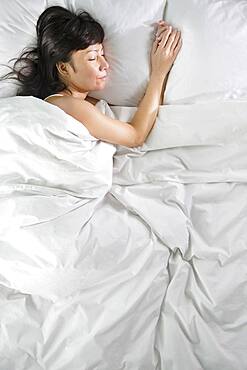 Mixed race woman sleeping in bed