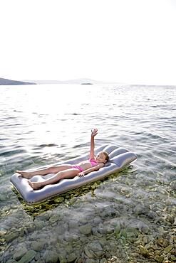 Caucasian girl floating on raft in lake