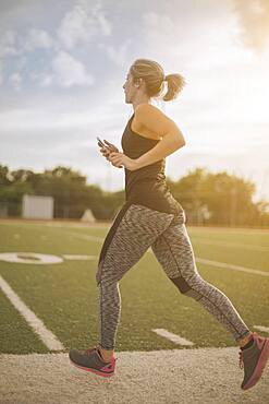 Caucasian athlete jogging on sports field