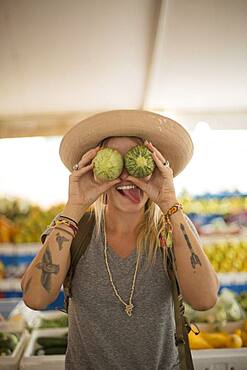 Caucasian woman making a face with fruit in farmers market