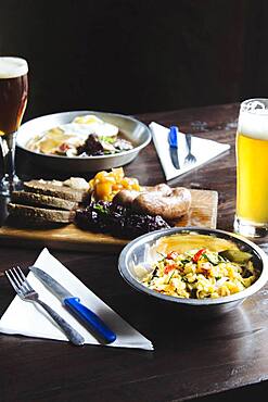 Bowl of pasta, cheese on cutting board and beer on table