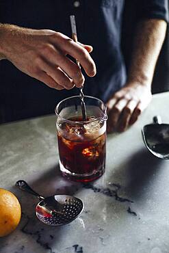 Caucasian bartender mixing cocktail in glass