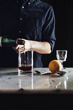 Caucasian bartender pouring cocktail in glass