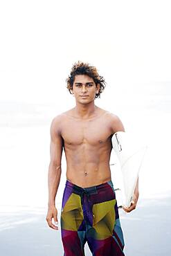 Man carrying surfboard on beach