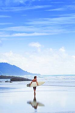 Man carrying surfboard on beach