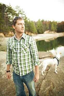 Man and dog standing near lake