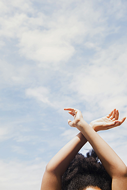 African American woman with arms raised to clouds