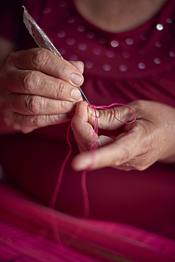 Hispanic woman weaving fabric on loom