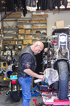 Caucasian man spraying lubricant on motorcycle