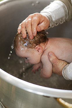 Priest baptizing baby girl with water