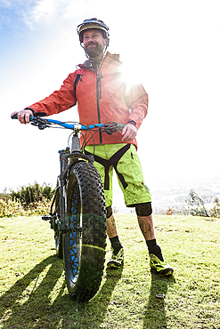 Portrait of smiling Caucasian man splattered in mud holding bicycle