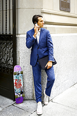 Caucasian businessman with skateboard talking on cell phone