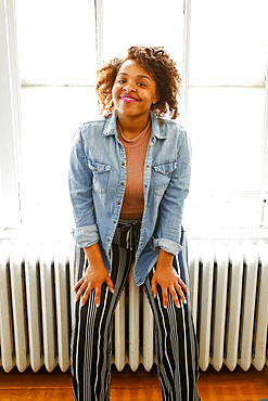 Smiling mixed race woman sitting on radiator