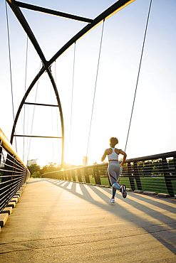 Distant mixed race woman running on bridge