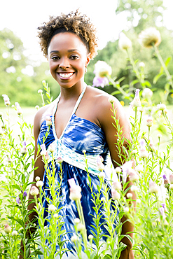 Portrait of smiling mixed race woman standing in wildflowers