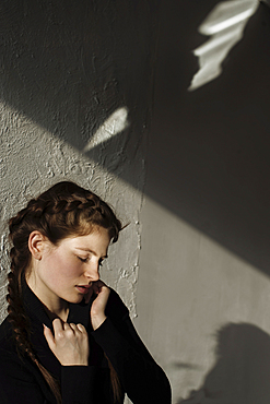 Shadow on wall over pensive Caucasian woman