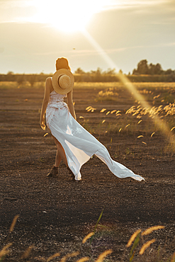 Sexy Caucasian woman wearing white dress walking in field