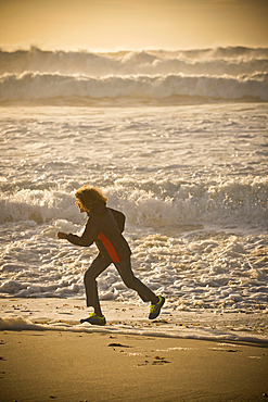 Mixed race boy running on beach