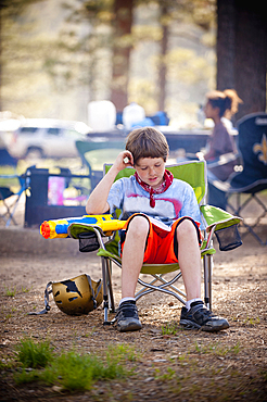 Caucasian boy reading book at campground