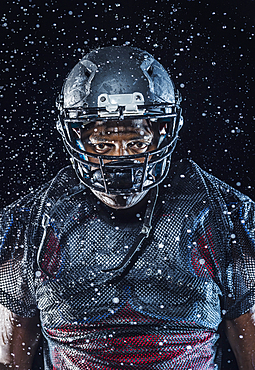 Water splashing on Black football player wearing helmet