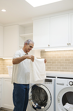 Caucasian man folding towel in modern laundry room