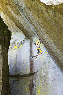 Mixed race boy hanging from rock