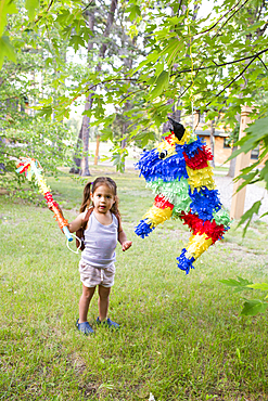 Mixed race girl hitting pinata outdoors