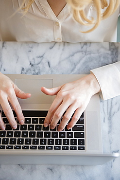 Hands of Caucasian woman typing on laptop