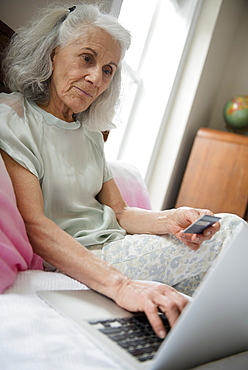 Older woman shopping online with credit card and laptop