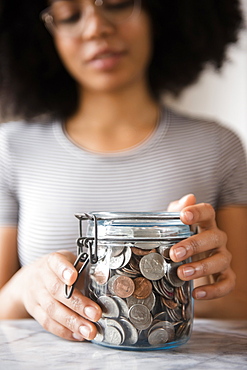 Smiling African American woman with jar full of coins