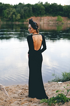 Middle Eastern woman wearing black dress near lake