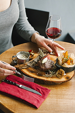 Woman eating meat with red wine