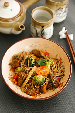 Chopsticks near bowl with noodles and meat