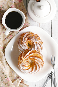 Pastry with powdered sugar on plate with coffee