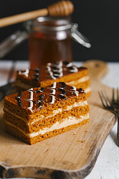 Slices of layer cake on cutting board with honey