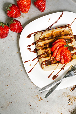 Sliced strawberries and chocolate syrup on waffle