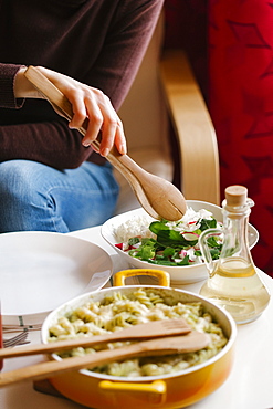 Woman serving salad with wooden tongs