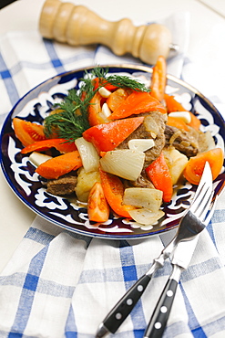 Meat and vegetables on plate with fork and knife