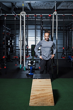 Mixed Race man looking at wooden platform in gymnasium