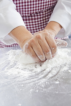 Hands of Hispanic woman kneading dough in flour